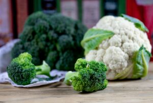 Close-up of fresh broccoli and cauliflower on a wooden table indoors.